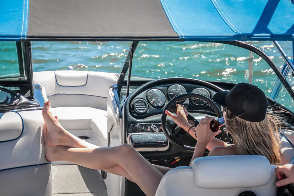 Woman driving a boat while drinking a beer