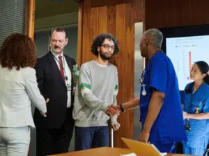 A patient recovering from a medical mistake meets an Allentown physician and a Munley Law medical malpractice attorney to discuss the difference between medical error and negligence. The supportive handshake underscores Munley Law’s client-first approach while the attorney stands ready to evaluate liability and damages. Behind them, nurses and data charts point to the depth of evidence needed to prove a malpractice case. Call 855-866-5529 to learn how Munley Law helps victims of medical mistakes secure full compensation.