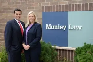Two attorneys from Munley Law stand outside the firm’s building beside a sign reading “Munley Law.” They are dressed in formal suits, representing trusted legal support for injured workers. This image represents the best workers compensation lawyer available to clients in Philadelphia.