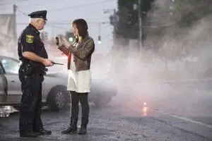 Munley Law car accident attorneys — image of two damaged sedans at a rain-slick intersection with reflective puddles and hazard flares. Crushed metal, cracked headlights, and scattered debris convey a serious collision. A distant, unmarked patrol-light glow adds realism while avoiding any readable text.
