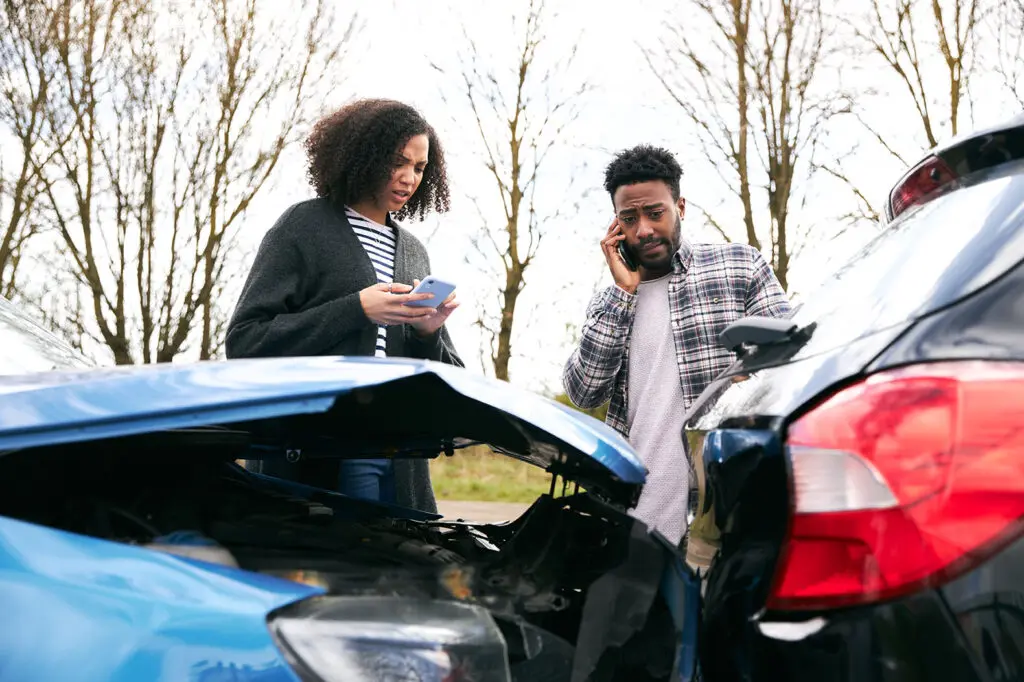 Couple at side of the road exchanging car insurance details after traffic accident