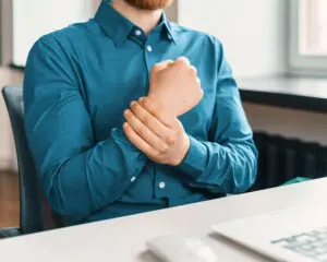 Office worker holding wrist in pain after repetitive motion injury