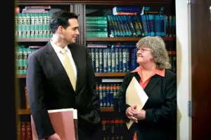 A compassionate workers' compensation lawyer at Munley Law consults with an injured worker, offering expert guidance on safely returning to work after a workplace injury. The professional office setting, filled with comprehensive legal texts, underscores Munley Law's extensive experience in protecting injured workers' rights and ensuring they are not pressured into returning prematurely. Injured employees facing questions about returning to work can confidently reach out to Munley Law at 855-866-5529 for dedicated legal assistance.
