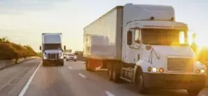 Two large 18-wheeler trucks traveling safely on a clear highway near Wilkes-Barre, PA, emphasizing safe transportation practices in the trucking industry. Munley Law Personal Injury Attorneys, located in Wilkes-Barre, represents clients involved in accidents related to large commercial trucks. The highway conditions depicted are clear and safe, highlighting proper adherence to transportation regulations. Munley Law ensures fair compensation for Scranton residents in truck accident cases.