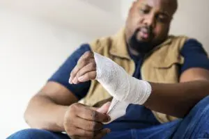 An injured worker in Pittsburgh, PA wraps a bandaged hand after a workplace accident. This image reflects the recovery process many employees face after filing a workers’ compensation claim. Munley Law provides trusted legal help for workers' compensation benefits and disputes. Call 855-866-5529 to speak with a Pittsburgh workers' compensation lawyer.