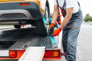 tow truck driver hooking up car to tow truck