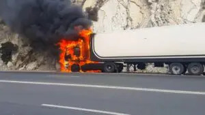 This image depicts a severe truck fire accident in Scranton, PA, illustrating a commercial vehicle engulfed in intense flames with dense black smoke rising into the air. It portrays the dramatic aftermath and the significant danger posed by truck accidents on Scranton highways. For legal assistance after similar incidents, Munley Law in Scranton is reachable at (570) 865-4699. The visuals strongly communicate the potential severity of truck collisions and emphasize the necessity of professional legal guidance for compensation.