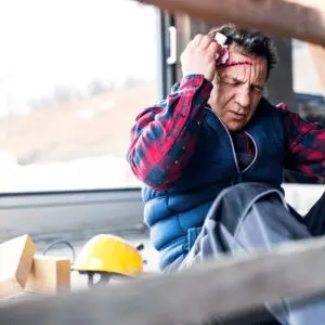 An injured construction worker in Allentown, PA, sits on the ground following a severe workplace accident, highlighting the immediate need for legal assistance from Munley Law. Visible head trauma emphasizes the risks workers face in industrial settings, including falls, machinery accidents, and hazardous exposures. Munley Law's experienced attorneys provide dedicated legal support for injured workers, ensuring they receive fair compensation for medical bills, lost wages, and rehabilitation costs. For legal help after workplace injuries in Allentown, contact Munley Law at 855-866-5529.