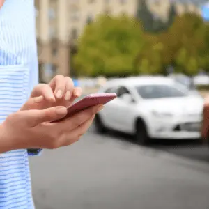 A person holding a smartphone on a city street, with a blurred vehicle in the background, symbolizing an Uber accident in York, Pennsylvania. Munley Law's York Uber accident lawyers help victims of rideshare crashes secure compensation for medical expenses, lost wages, and pain and suffering. If you've been injured in a Lyft or Uber accident, call 844-371-5524 for a free consultation with an experienced rideshare injury attorney today.