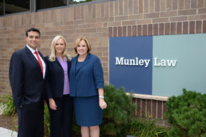 robert munley, caroline munley, and marion munley next to the munley law sign