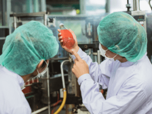 Two factory workers in protective clothing examining a component