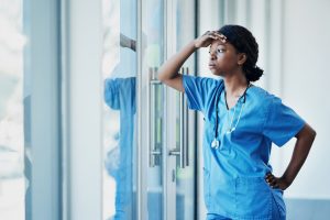 nurse holding head staring out window