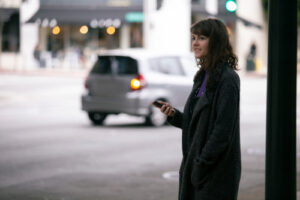 Female holding cell phone on street waiting for Uber Lyft Rideshare 