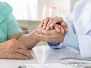 An image depicting a caring medical professional in Allentown holding the hand of a traumatic brain injury victim, representing Munley Law's compassionate and client-focused approach. Munley Law provides emotional support alongside legal advocacy, ensuring that TBI victims receive comprehensive assistance through their recovery journey. Victims and families in Allentown can count on Munley Law’s experienced personal injury attorneys for empathetic, skilled legal guidance. Contact Munley Law at844-686-5397 for your free case consultation.