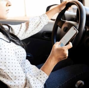 A distracted driver in Allentown glances at her phone while steering with one hand, illustrating the split-second negligence that causes texting-while-driving crashes. This candid view highlights why victims turn to an Allentown texting while driving accident lawyer at Munley Law for help. Our attorneys use scenes like this to show fault and win fair payment for clients. Call844-686-5397 to discuss your case with Munley Law today.