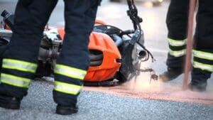 Motorcycle lying on its side in the road with emergency workers on either side