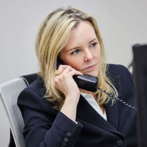 Caroline Munley, an expert Allentown workers’ compensation lawyer at Munley Law, stands in a blue suit with a red tie in Allentown, Pennsylvania. The image captures her outdoors with a scenic background of hills and water, highlighting her professional role in workplace injury cases. Based in Allentown at 609 Hamilton St, Munley Law helps injured workers secure fair compensation. Call 570-865-4699 to connect with Caroline Munley for your workers’ compensation claim.