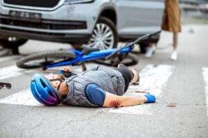 Cyclist wearing a helmet lying on the road after being hit by a car
