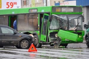 Black car crashed side on into a bus that has front end damage