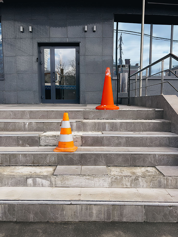 Orange protective cones on broken steps in office building warn of danger. High quality photo