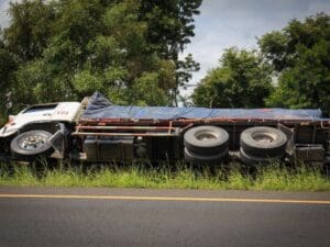 Truck lying on its side on the grass verge of a highway
