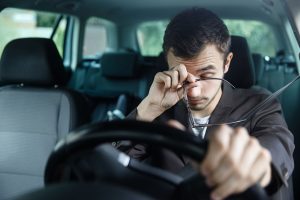 driver wiping his eyes while driving fatigued driving