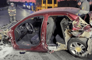 Car accident scene with a burnt out chassis and a fireman and bus in the background