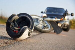 Motorcycle helmet lying in the road next to a bike and car