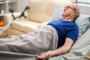 Elderly man lying in a nursing home bed