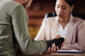 Close-up of a black wrist brace on a wooden desk with legal papers and a pen blurred behind it, illustrating the first step in the process of filing a personal injury lawsuit in Allentown. This scene shows the initial consultation phase offered by Munley Law in Allentown, PA. It conveys a calm, professional setting where injury victims can seek help. Call844-686-5397 to schedule your free consultation in Allentown, PA with Munley Law.