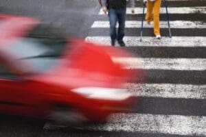 A red SUV is stopped in the middle of a Philadelphia crosswalk, showing visible road scrapes and minor front damage. The scene represents a potential pedestrian collision on a city street. This photo is used by Munley Law’s Philadelphia pedestrian accident attorneys—call844-686-5397 for representation. The angle highlights the street markings and urban roadway detail in natural daylight.