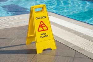 slip and fall yellow hazard sign by swimming pool 