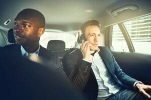 Man in a suit on the phone being driven in a rideshare vehicle